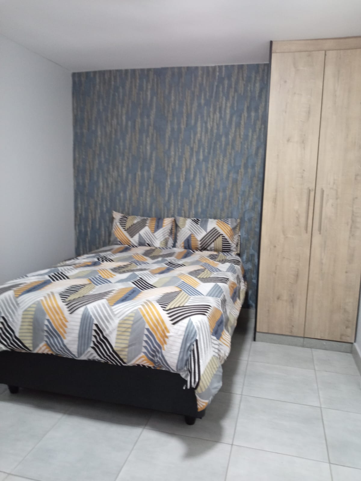 Double bed with patterned linen and feature wall